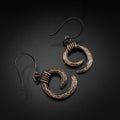 Copper spiral earrings flat lay, grey background, overhead view — Vortex