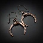 Lunar Horns copper crescent earrings — flat lay on dark background