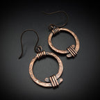 Copper open ring earrings flat lay, dark background, showing wire coil wraps — Torque