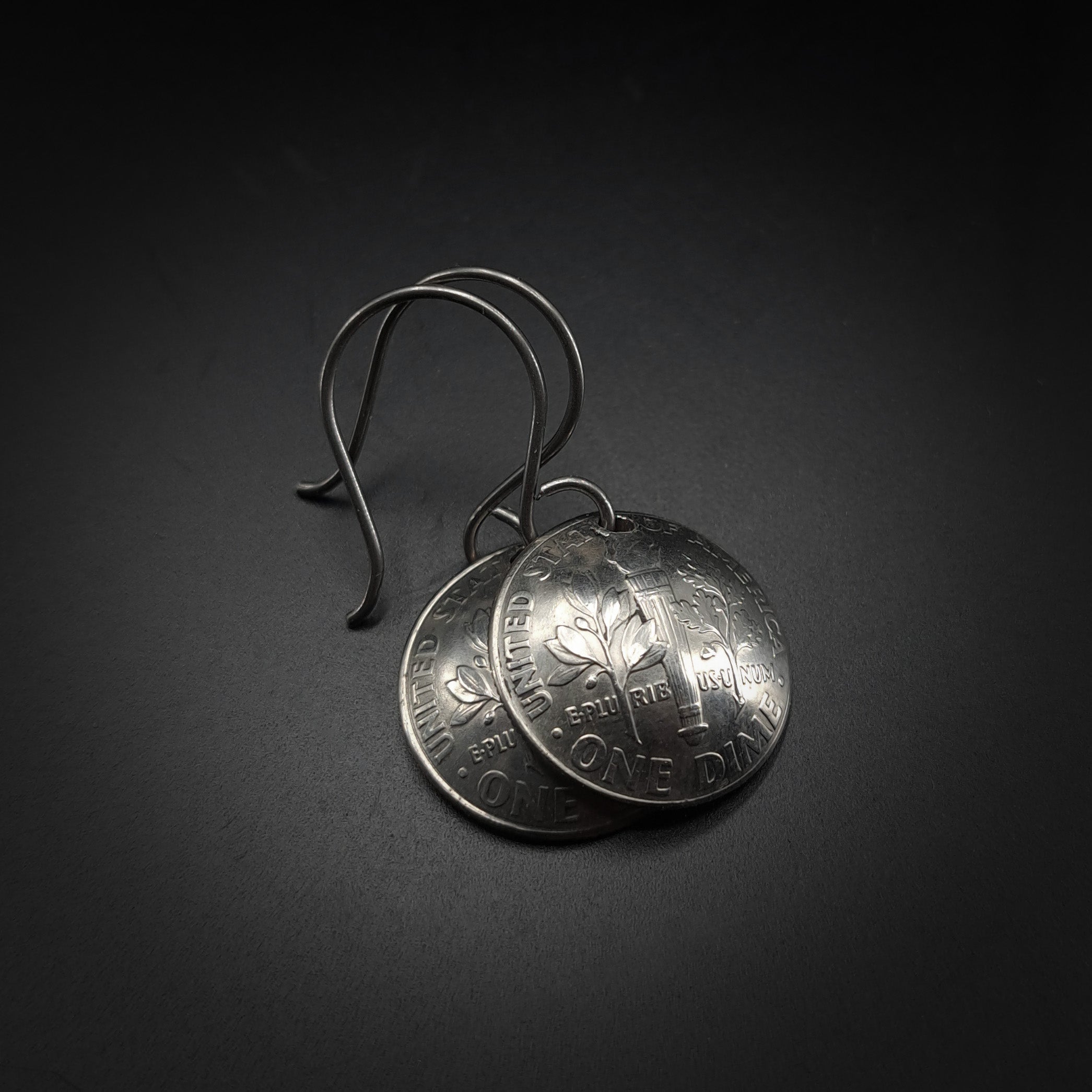 Pair of silver coin earrings on a dark background