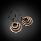 Pair of copper hoop earrings on a dark background