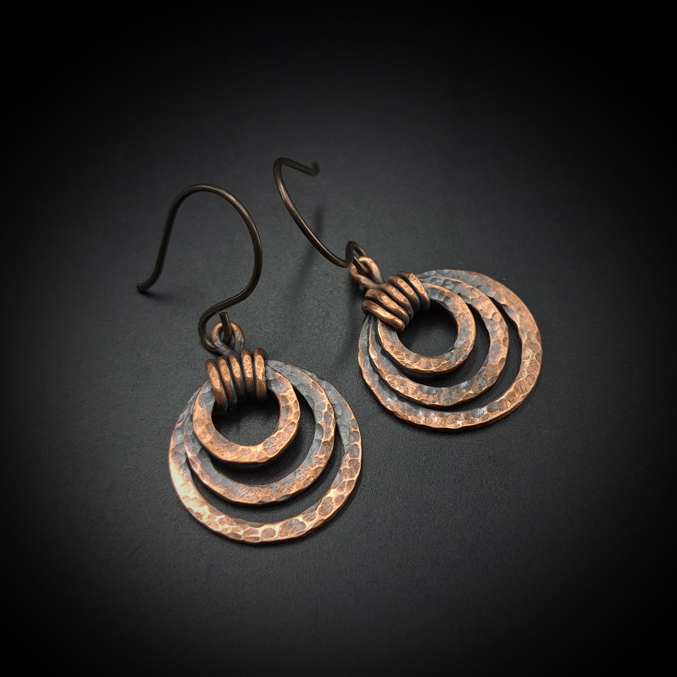 Pair of copper hoop earrings on a dark background