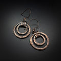 Copper double hoop earrings with coiled wire — dark background