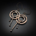 Hammered copper double ring earrings flat lay, dark background — wire wrap detail close-up