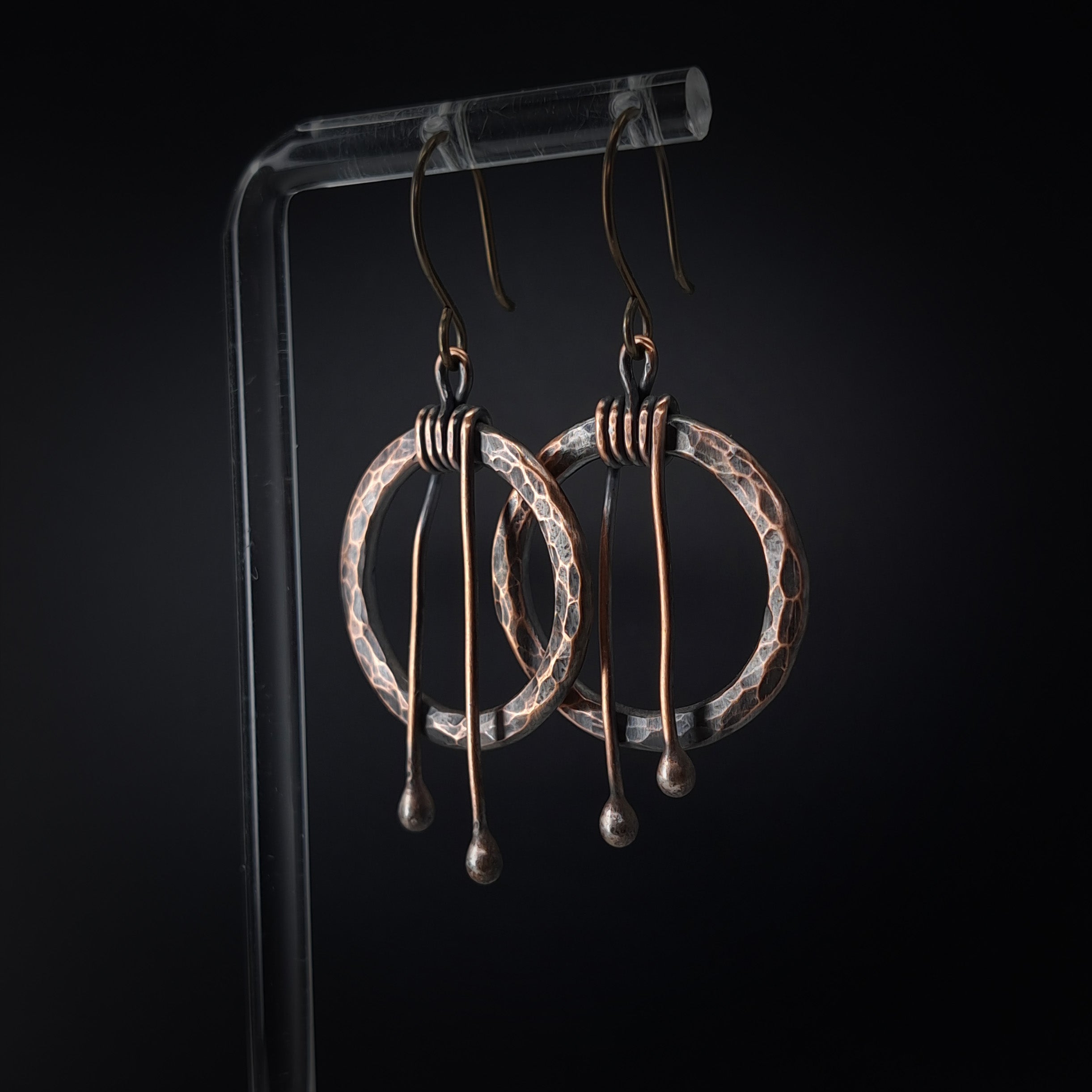 Hammered copper hoop earrings on acrylic stand, black background — wire wrap close-up