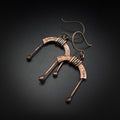 Copper arch earrings flat lay, dark background, angled view — U-Turn