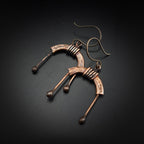 Copper arch earrings flat lay, dark background, angled view — U-Turn