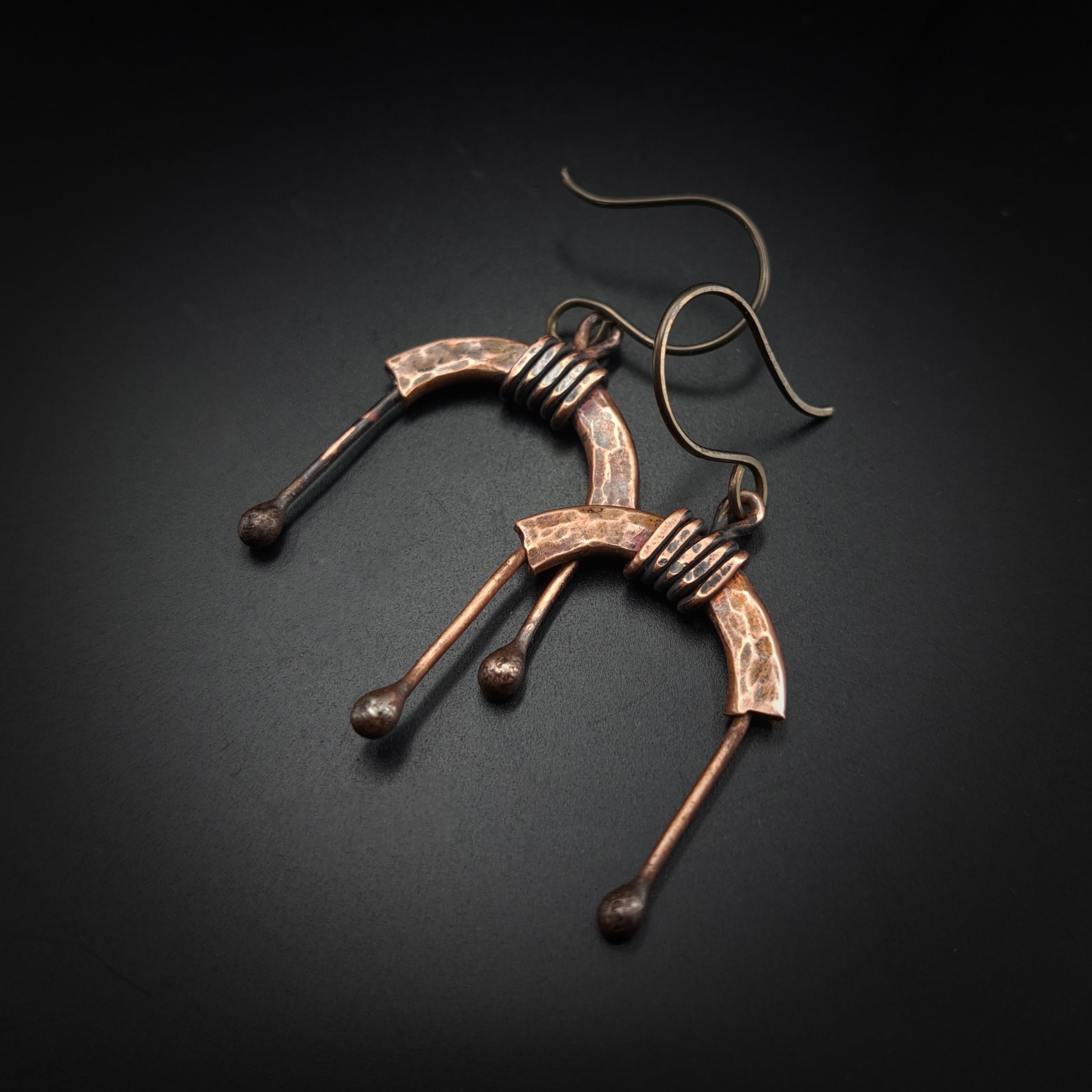 Copper arch earrings flat lay, dark background, angled view — U-Turn