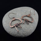 Copper fringe earrings on natural river stone, dark background — Nimbus Storm