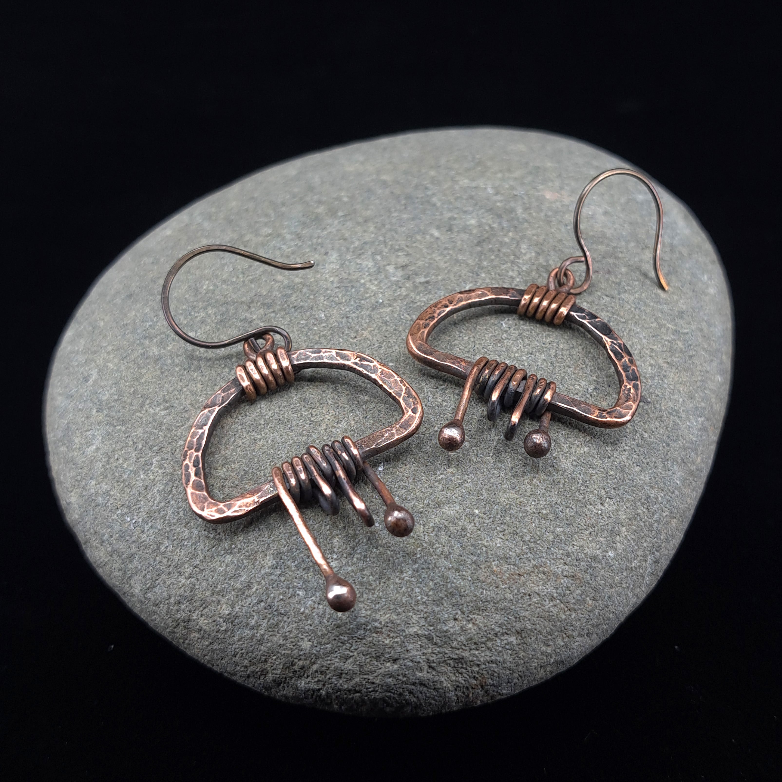 Copper fringe earrings on natural river stone, dark background — Nimbus Storm