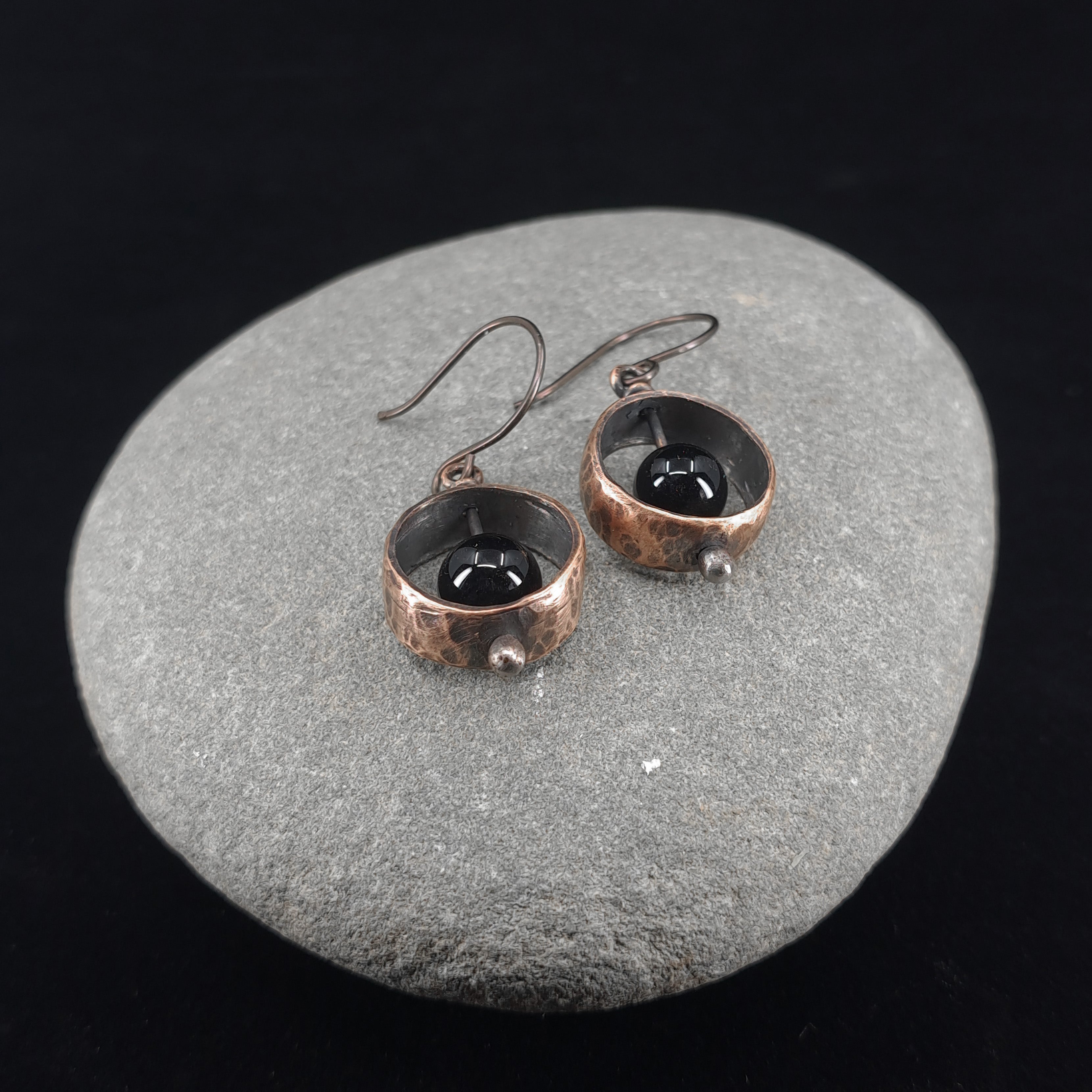 Copper & black onyx earrings flat lay, grey stone background, overhead view — Meridian