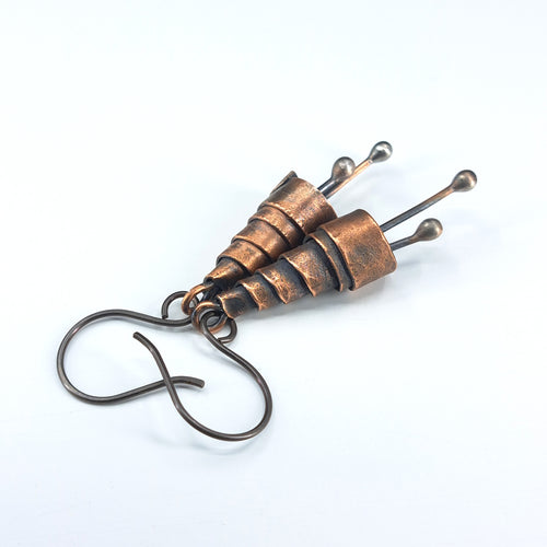 Copper spiral earrings close-up detail, white background — coiled cone design