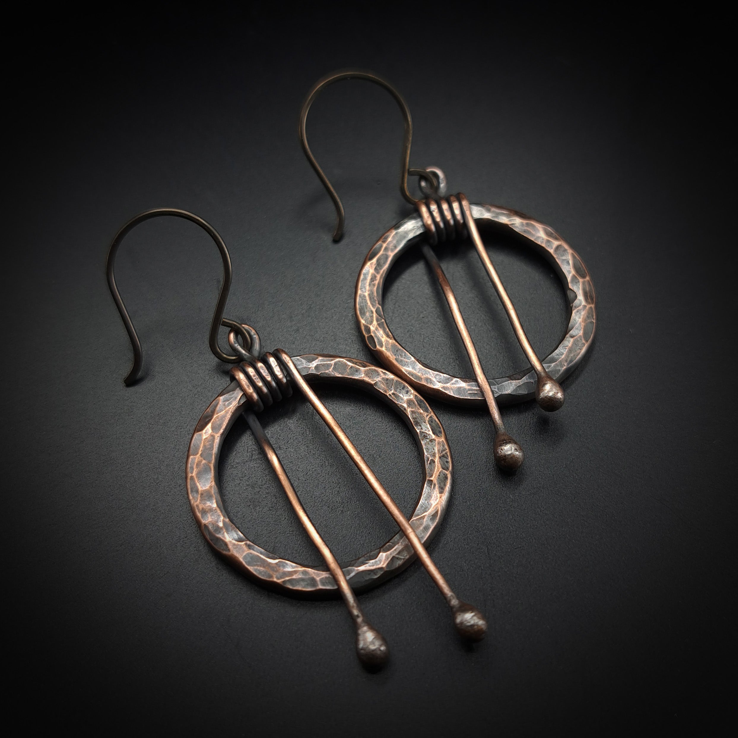 Hammered copper hoop earrings pair, black background — oxidized copper, handmade niobium hooks