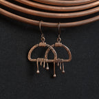 Earrings hanging on copper wire coil, dark fabric background — Nimbus Storm