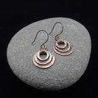 Rustic copper earrings on a stone surface