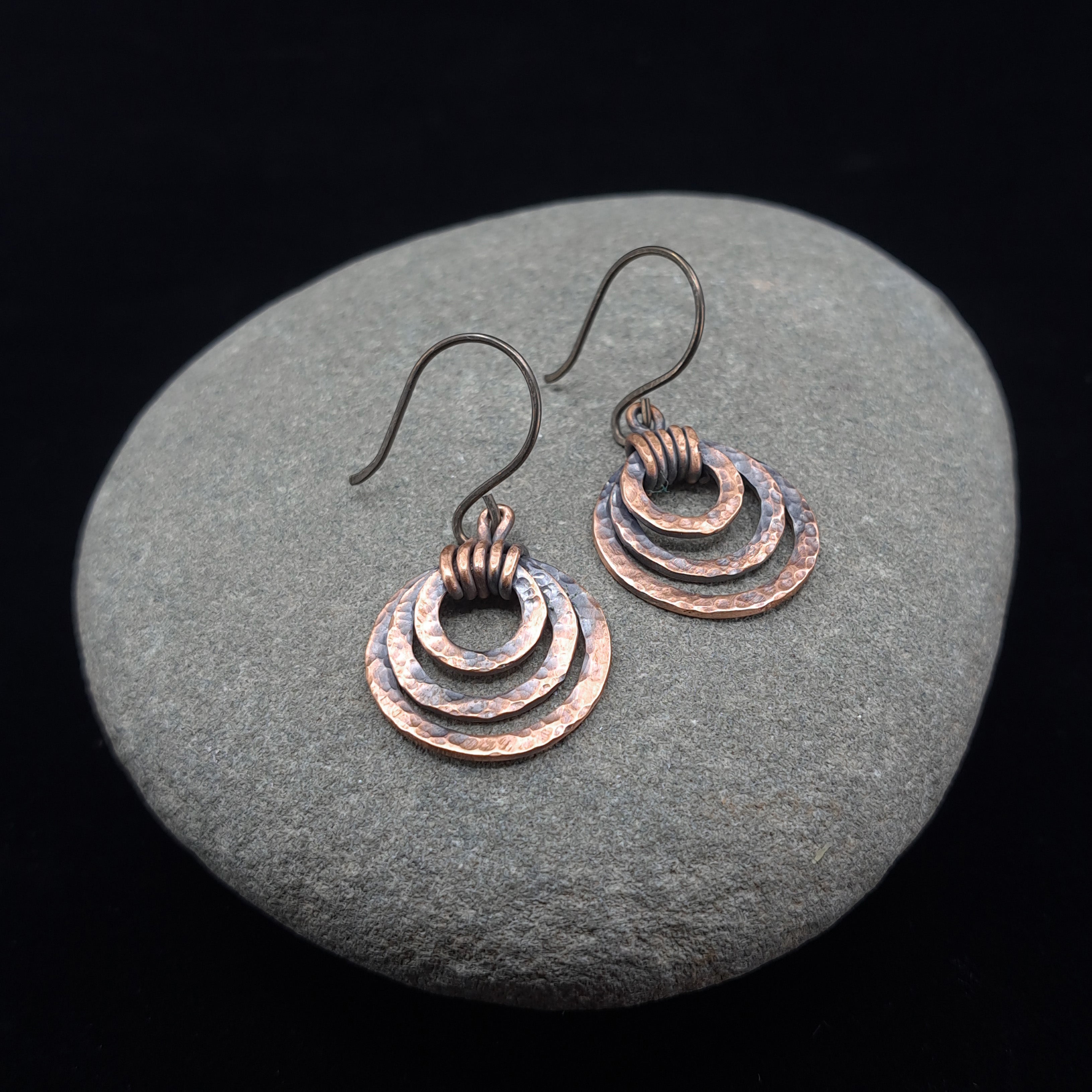 Rustic copper earrings on a stone surface
