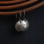 Vintage Currency dime earrings hanging on copper coil — dark fabric background