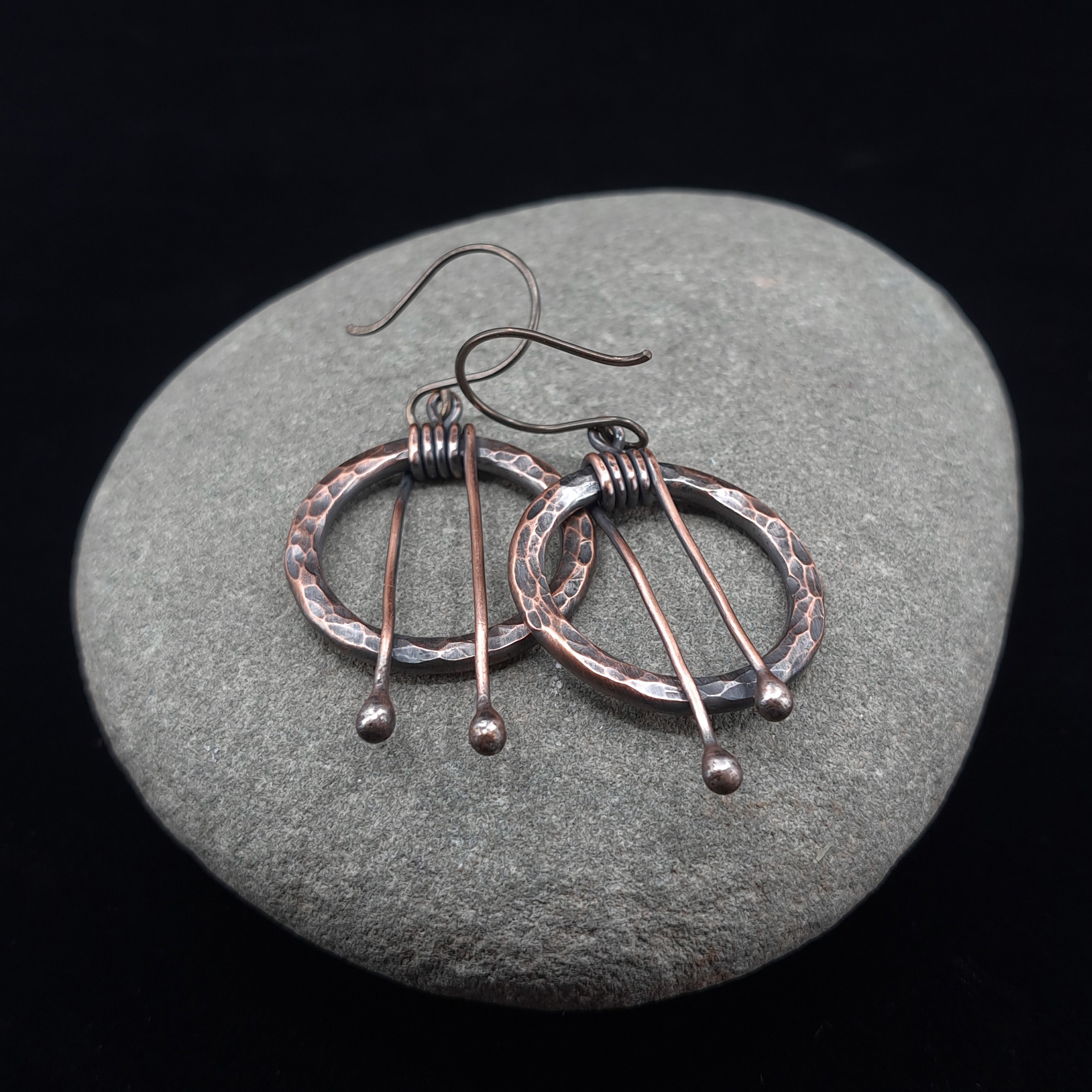 Hammered copper hoop earrings on gray stone — ball drop detail, niobium hooks.