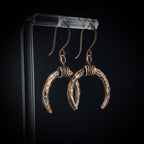 Lunar Horns earrings on acrylic stand — dark background, side view