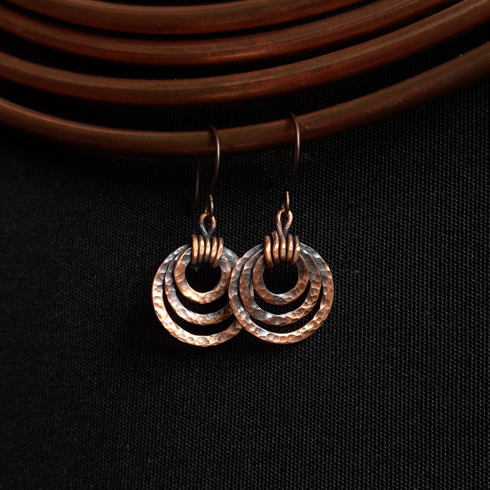 Copper earrings with circular design on a black background