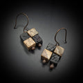 Terra Mosaic earrings on acrylic stand — side view, dark background