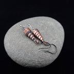Copper earrings on a gray stone surface with a black background