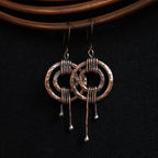 Hammered copper double ring earrings on black background — sculptural copper statement earrings