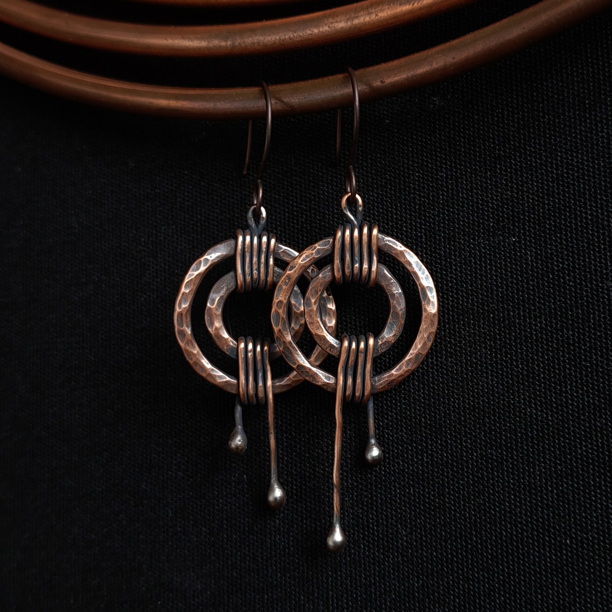Hammered copper double ring earrings on black background — sculptural copper statement earrings