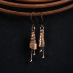 Copper spiral earrings hanging on copper wire, black background — oxidized finish