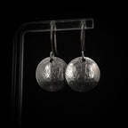 Vintage Currency dime earrings on acrylic stand — black background, front view