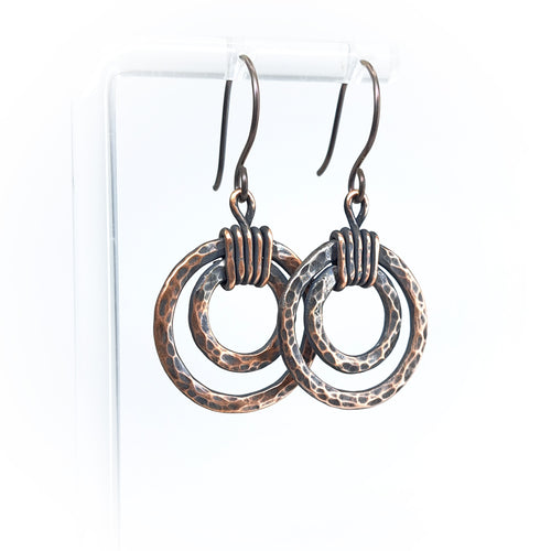 Copper double hoop earrings with coiled wire on white display