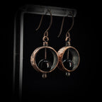 Copper & black onyx earrings on acrylic stand, dark background, warm light — Meridian