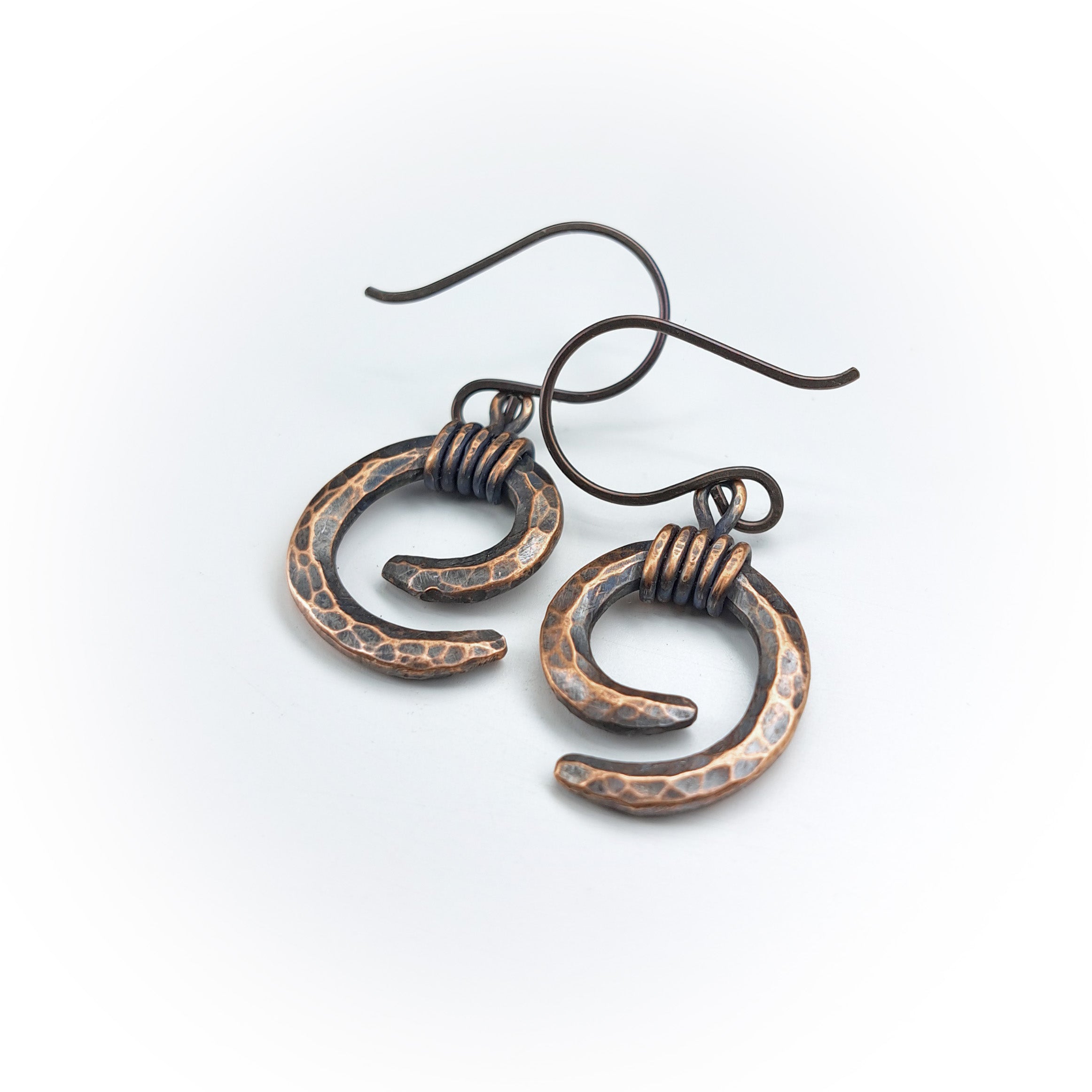 Copper spiral earrings flat lay, white background, angled view — Vortex