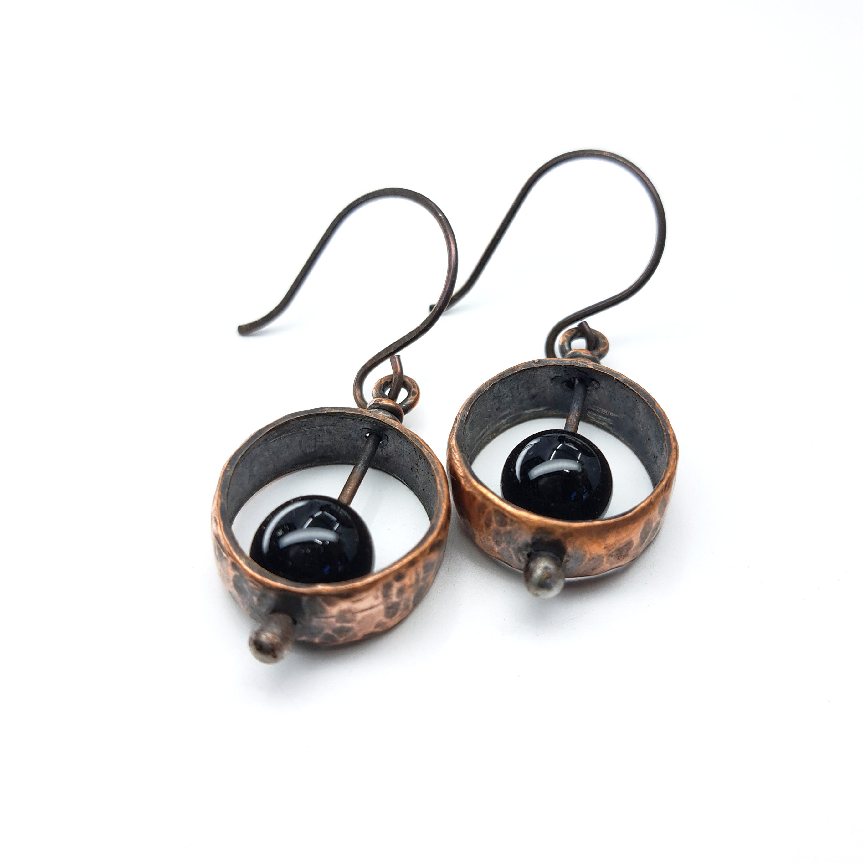 Copper & black onyx earrings flat lay, white background, top-down view showing depth — Meridian