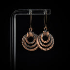 Hammered copper ring earrings — triple hoop dangle, black background, handmade