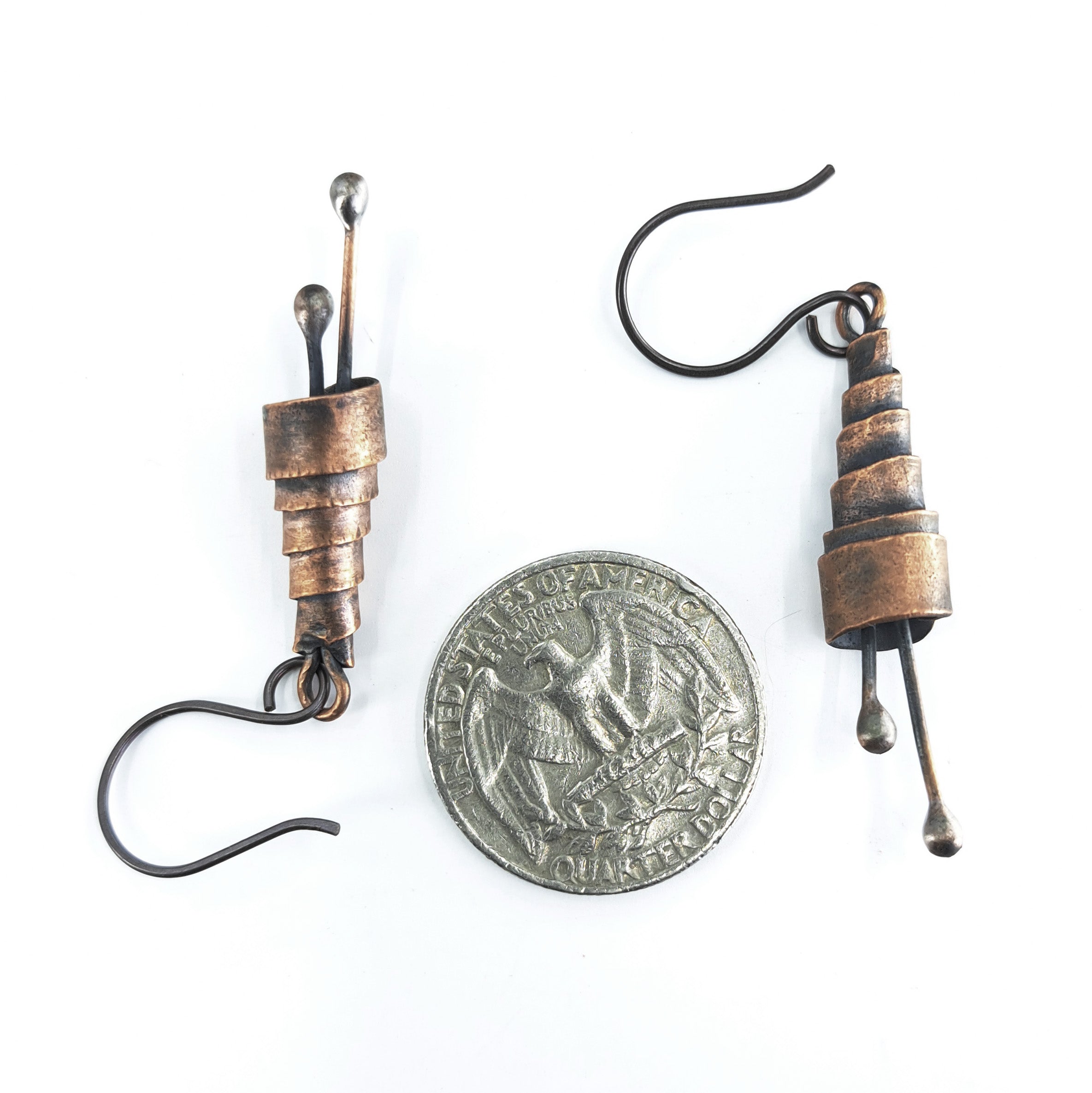 Copper spiral earrings with quarter coin for size reference — smaller than a quarter, white background.