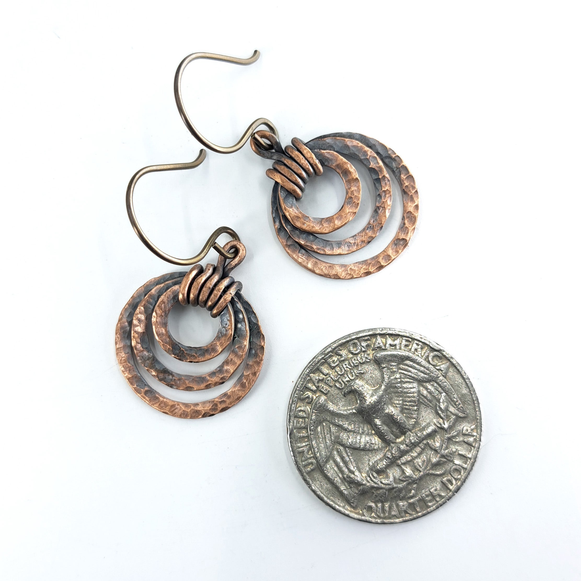 Small hammered copper ring earrings next to a quarter coin for size reference — smaller than a quarter, handmade.